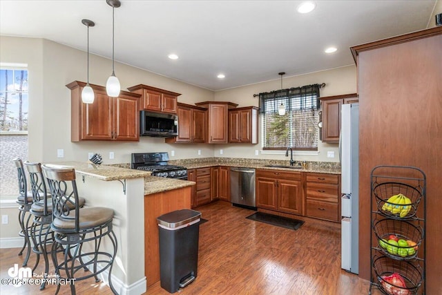 7865 S Settlers Bay Dr, Wasilla, AK 99623 - kitchen with a sink, a kitchen breakfast bar, stainless steel appliances, a peninsula, and dark wood-style floors