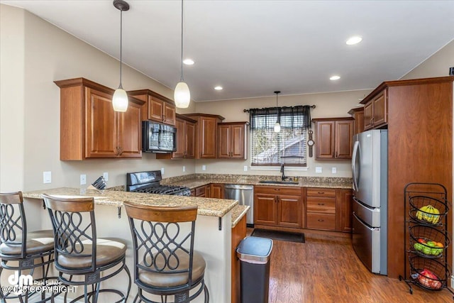 7865 S Settlers Bay Dr, Wasilla, AK 99623 - kitchen with a peninsula, dark wood-type flooring, a sink, appliances with stainless steel finishes, and decorative light fixtures