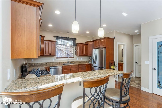 7865 S Settlers Bay Dr, Wasilla, AK 99623 - kitchen with brown cabinetry, a sink, appliances with stainless steel finishes, and a peninsula