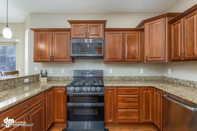 7865 S Settlers Bay Dr, Wasilla, AK 99623 - kitchen with appliances with stainless steel finishes, light stone countertops, brown cabinets, and wood finished floors