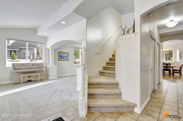 stairway featuring recessed lighting, arched walkways, baseboards, and tile patterned floors