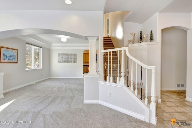 staircase with arched walkways, baseboards, and visible vents