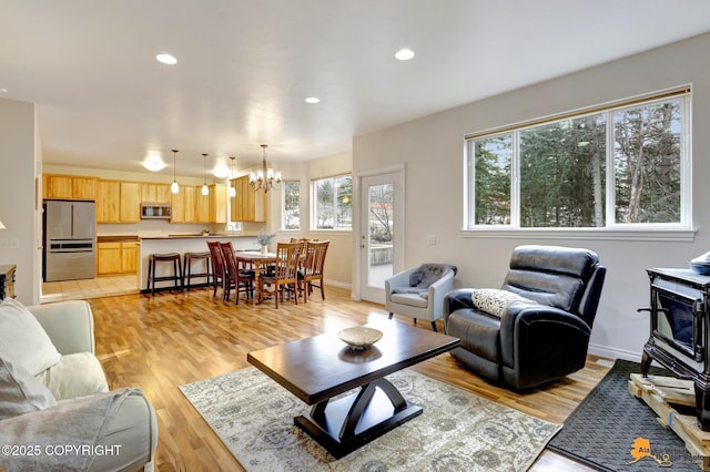 living area with a chandelier, plenty of natural light, and light wood-style flooring