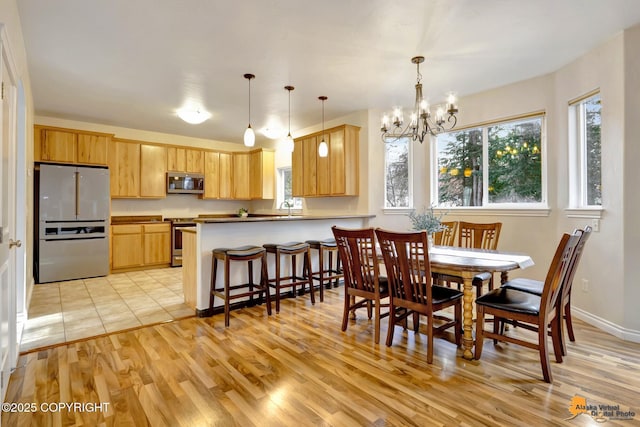 dining room with baseboards, an inviting chandelier, and light wood finished floors