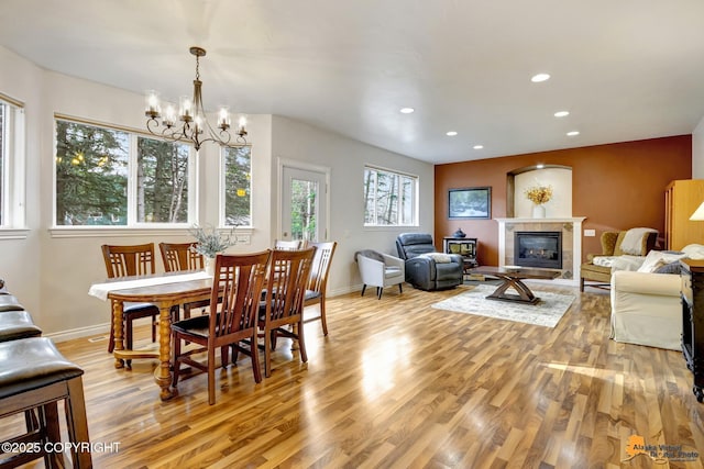 dining area featuring a fireplace, light wood-style floors, a chandelier, recessed lighting, and baseboards