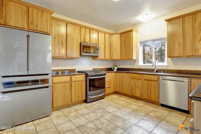 kitchen featuring dark stone counters, stainless steel appliances, and a sink