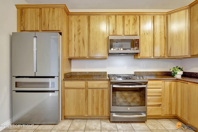 kitchen featuring dark stone counters, light brown cabinets, stainless steel appliances, and light tile patterned flooring
