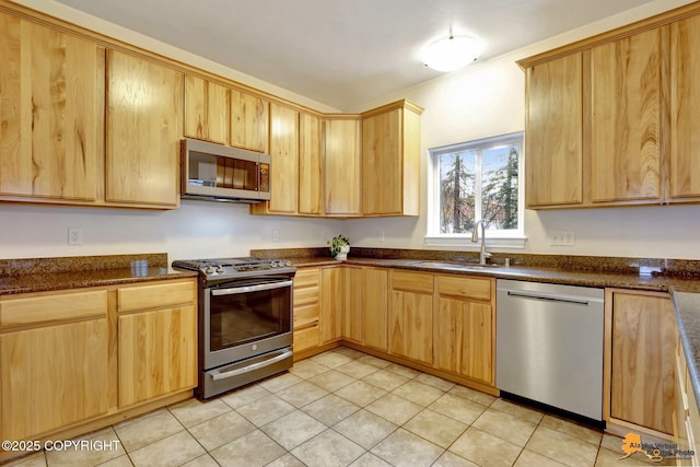 kitchen featuring appliances with stainless steel finishes, a sink, and light brown cabinets