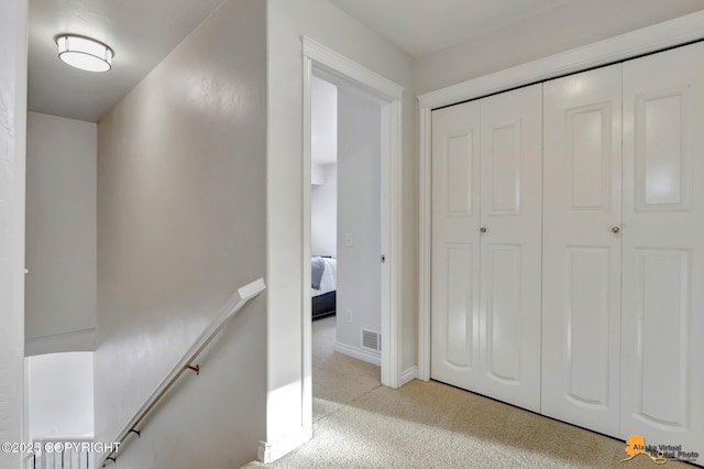corridor with baseboards, carpet flooring, visible vents, and an upstairs landing