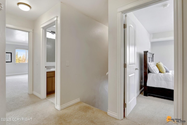 corridor with baseboards and light carpet