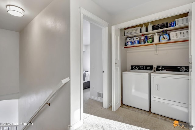 washroom featuring washing machine and clothes dryer, laundry area, light colored carpet, baseboards, and visible vents