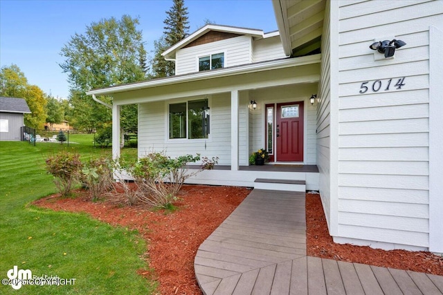 view of exterior entry featuring a porch and a yard