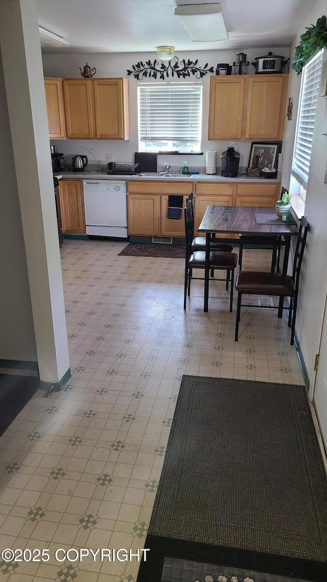 kitchen featuring visible vents, a sink, light floors, and dishwasher