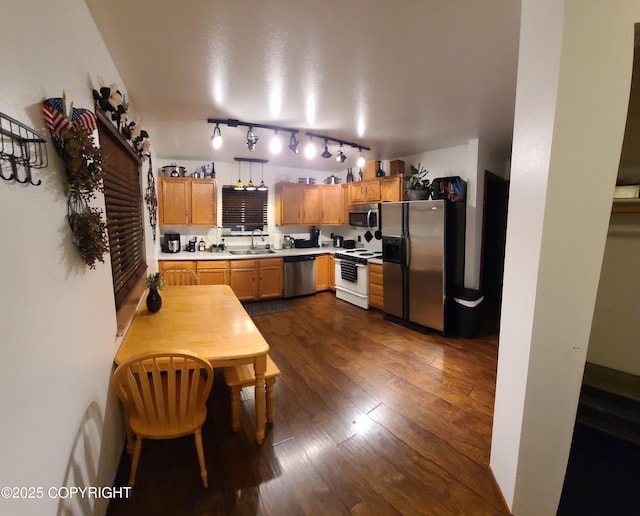 kitchen with light countertops, stainless steel appliances, a sink, and dark wood-type flooring