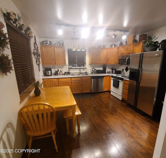 kitchen featuring light countertops, dark wood-style flooring, appliances with stainless steel finishes, and a sink
