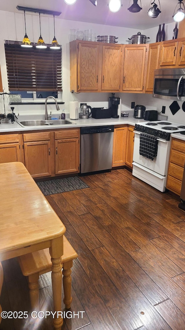 kitchen featuring light countertops, stainless steel appliances, a sink, and dark wood-type flooring