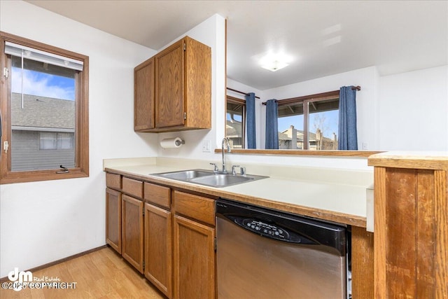 4241 Folker St # D202, Anchorage, AK 99508 - kitchen with brown cabinetry, stainless steel dishwasher, light wood-type flooring, a sink, and light countertops