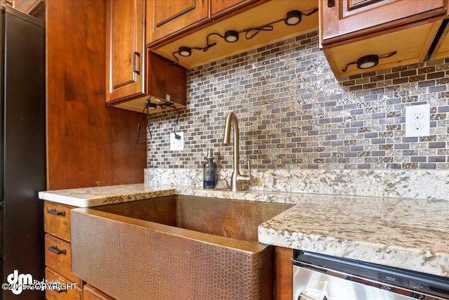 337 Alta Dr, Girdwood, AK 99587 - kitchen with stainless steel dishwasher, brown cabinetry, tasteful backsplash, light stone counters, and a sink