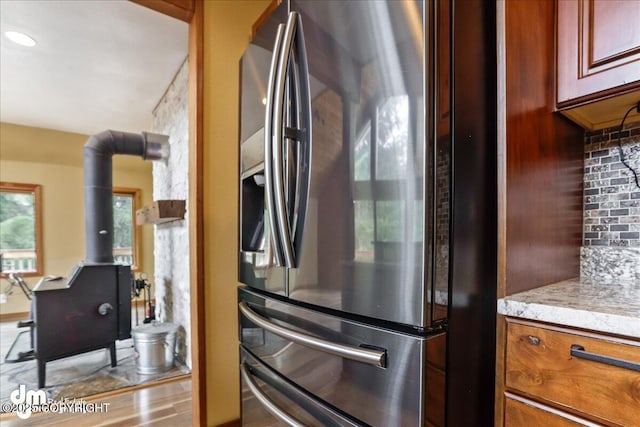 337 Alta Dr, Girdwood, AK 99587 - kitchen featuring backsplash, light stone countertops, stainless steel fridge with ice dispenser, and a wood stove