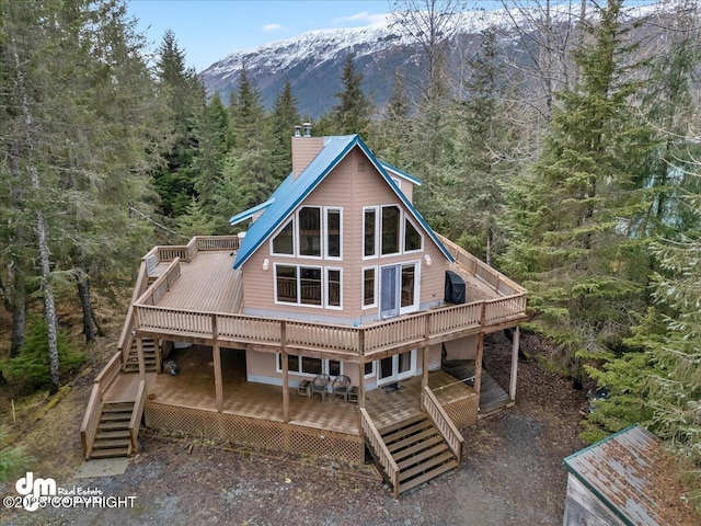 337 Alta Dr, Girdwood, AK 99587 - back of property featuring a chimney, stairway, a deck with mountain view, and a wooded view