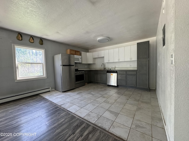 3140 N Brocton Ave, Wasilla, AK 99654 - kitchen with a textured wall, appliances with stainless steel finishes, a sink, a textured ceiling, and a baseboard heating unit