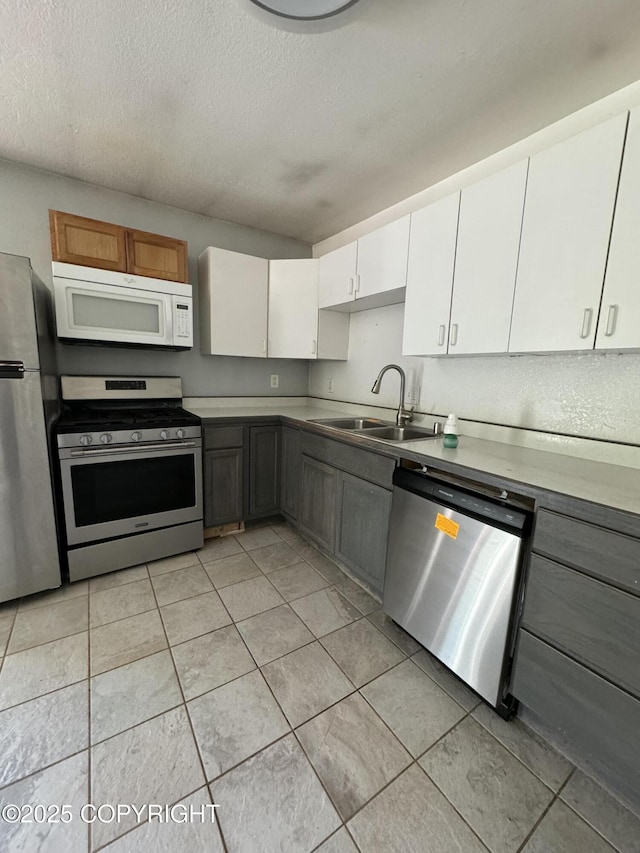 3140 N Brocton Ave, Wasilla, AK 99654 - kitchen featuring appliances with stainless steel finishes, a sink, a textured ceiling, white cabinetry, and light tile patterned floors