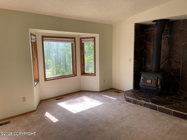 5875 E Alder Cir, Wasilla, AK 99654 - unfurnished living room with visible vents, a wood stove, and carpet floors