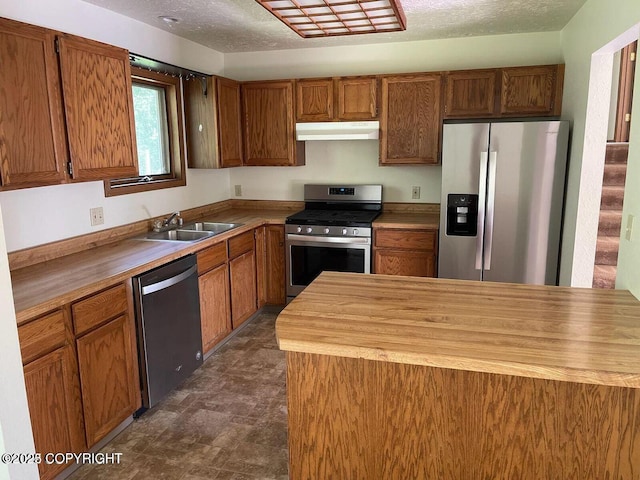 5875 E Alder Cir, Wasilla, AK 99654 - kitchen featuring brown cabinetry, under cabinet range hood, a sink, wood counters, and stainless steel appliances