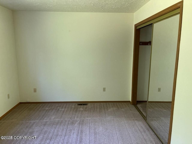 5875 E Alder Cir, Wasilla, AK 99654 - unfurnished bedroom with visible vents, a textured ceiling, carpet, and a closet