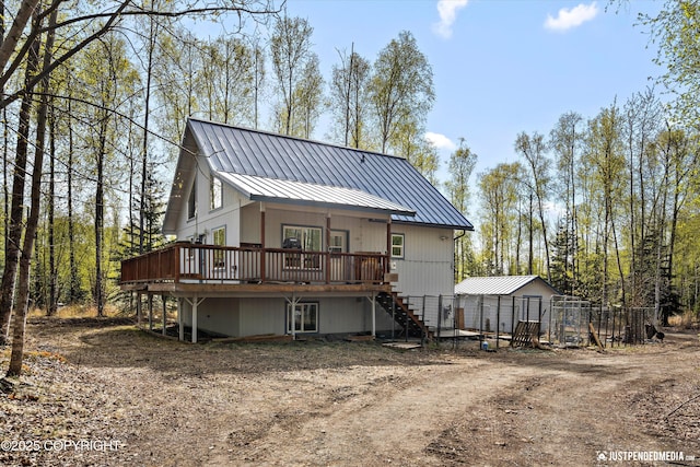 rear view of property with stairs, driveway, metal roof, a wooden deck, and a standing seam roof