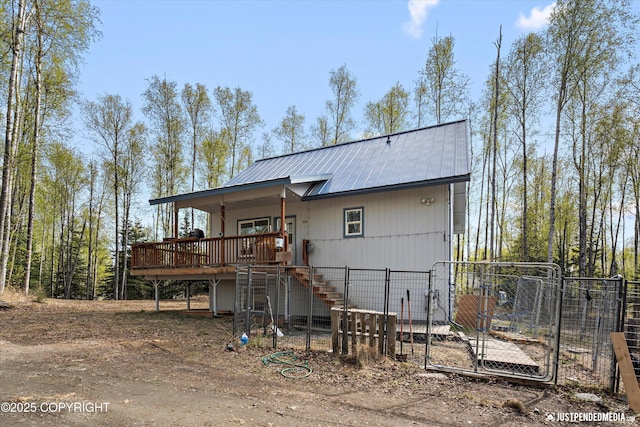 back of property featuring fence, metal roof, a deck, stairway, and a gate