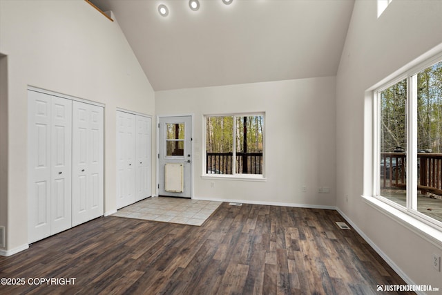 entrance foyer featuring baseboards, visible vents, high vaulted ceiling, and wood finished floors