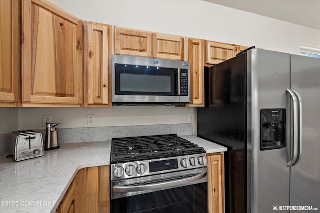 kitchen featuring light stone counters and appliances with stainless steel finishes