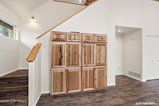 interior space featuring baseboards, high vaulted ceiling, visible vents, and wood finished floors
