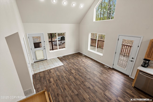 foyer entrance with baseboards, visible vents, dark wood finished floors, and high vaulted ceiling