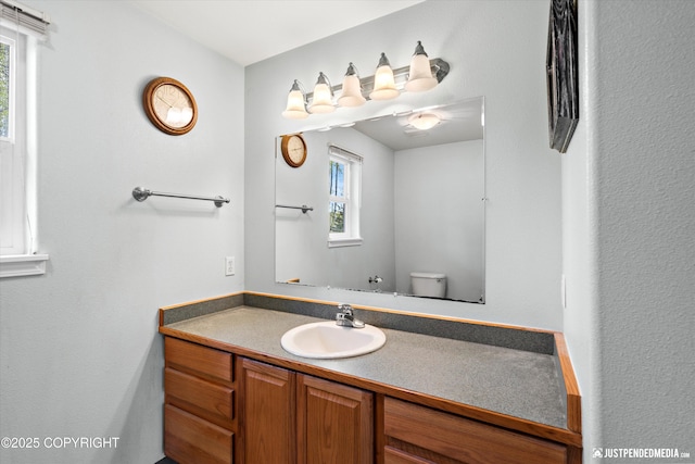 bathroom featuring toilet, vanity, and plenty of natural light