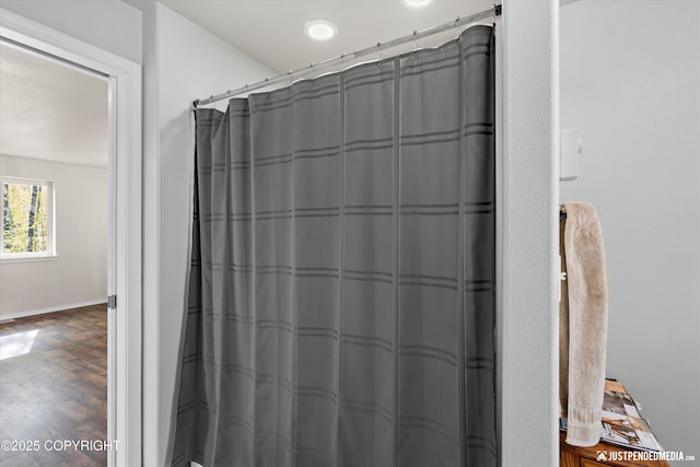 bathroom with a shower with curtain, baseboards, and wood finished floors