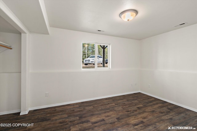 spare room featuring baseboards, visible vents, and wood finished floors