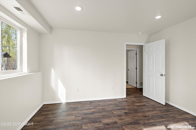 unfurnished room with dark wood-type flooring, baseboards, visible vents, and recessed lighting