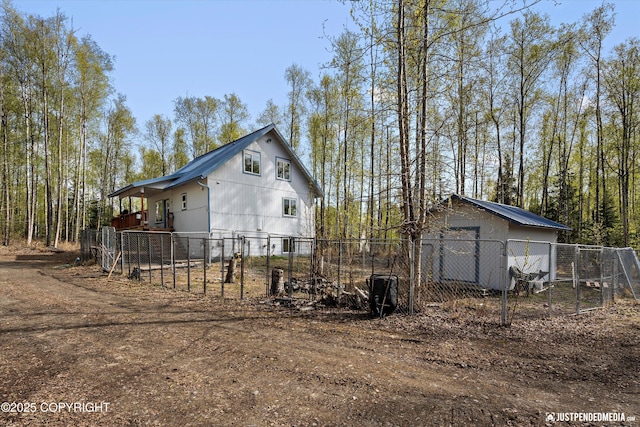 view of side of property featuring fence, a detached garage, and an outbuilding