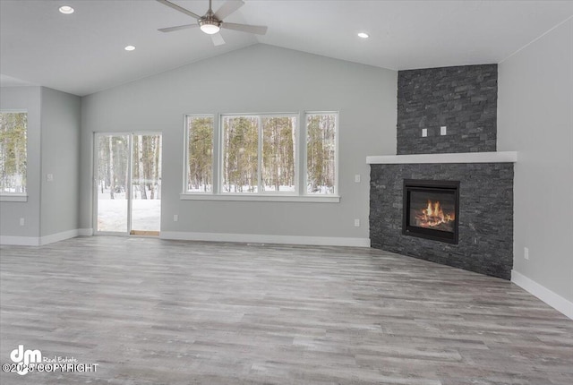 unfurnished living room with wood finished floors, lofted ceiling, a fireplace, baseboards, and ceiling fan