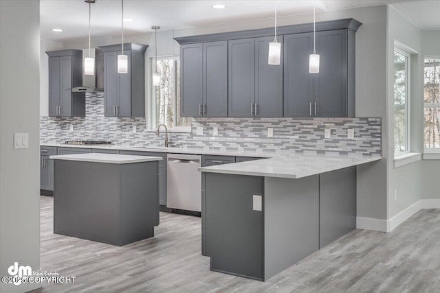 kitchen with wall chimney range hood, backsplash, appliances with stainless steel finishes, and plenty of natural light
