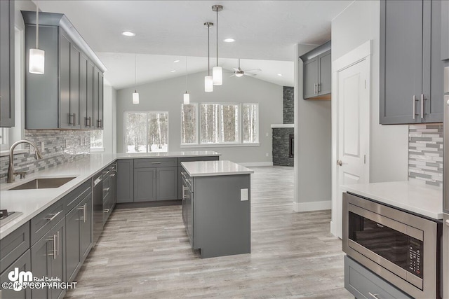 kitchen featuring a ceiling fan, a sink, gray cabinetry, lofted ceiling, and stainless steel appliances
