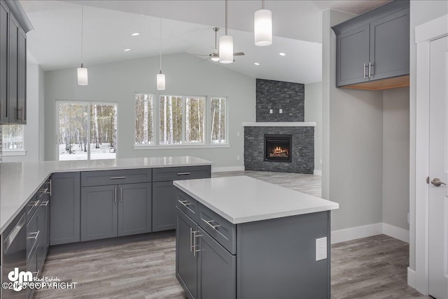 kitchen featuring lofted ceiling, light wood-type flooring, light countertops, gray cabinets, and a ceiling fan