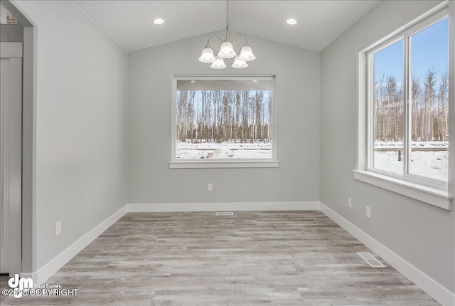 unfurnished dining area featuring an inviting chandelier, baseboards, lofted ceiling, and wood finished floors