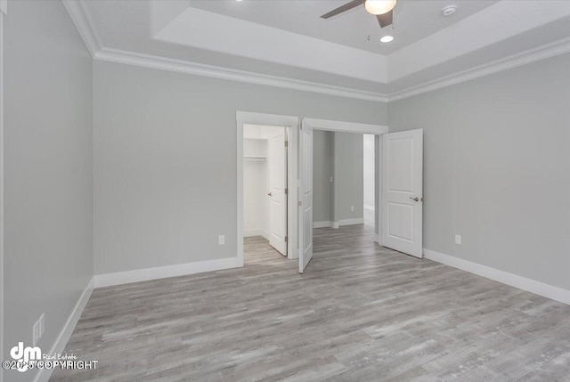 unfurnished bedroom featuring ornamental molding, wood finished floors, and a raised ceiling