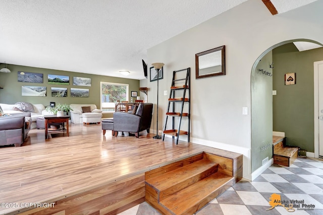 living room featuring arched walkways, a textured ceiling, and baseboards