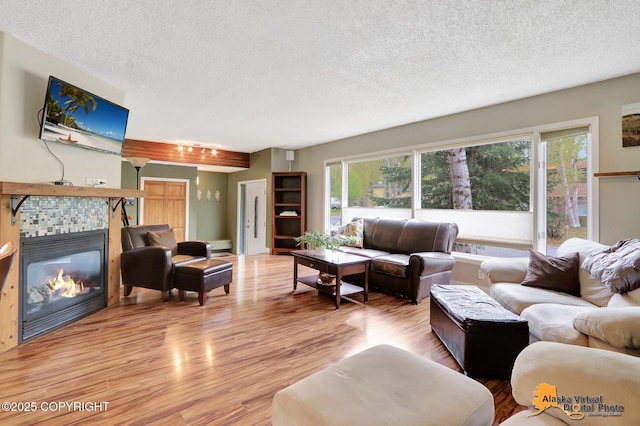 living room featuring a textured ceiling, wood finished floors, plenty of natural light, and a tile fireplace