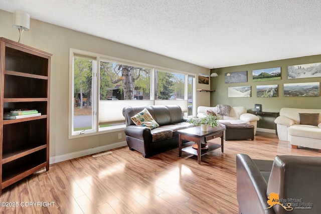 living area with wood finished floors, a textured ceiling, and baseboards