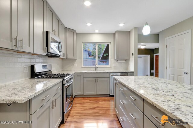 kitchen featuring stainless steel appliances, gray cabinetry, decorative backsplash, light wood-type flooring, and recessed lighting